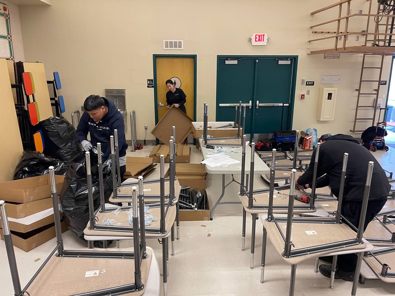 Large quantity of school chairs and tables being assembled