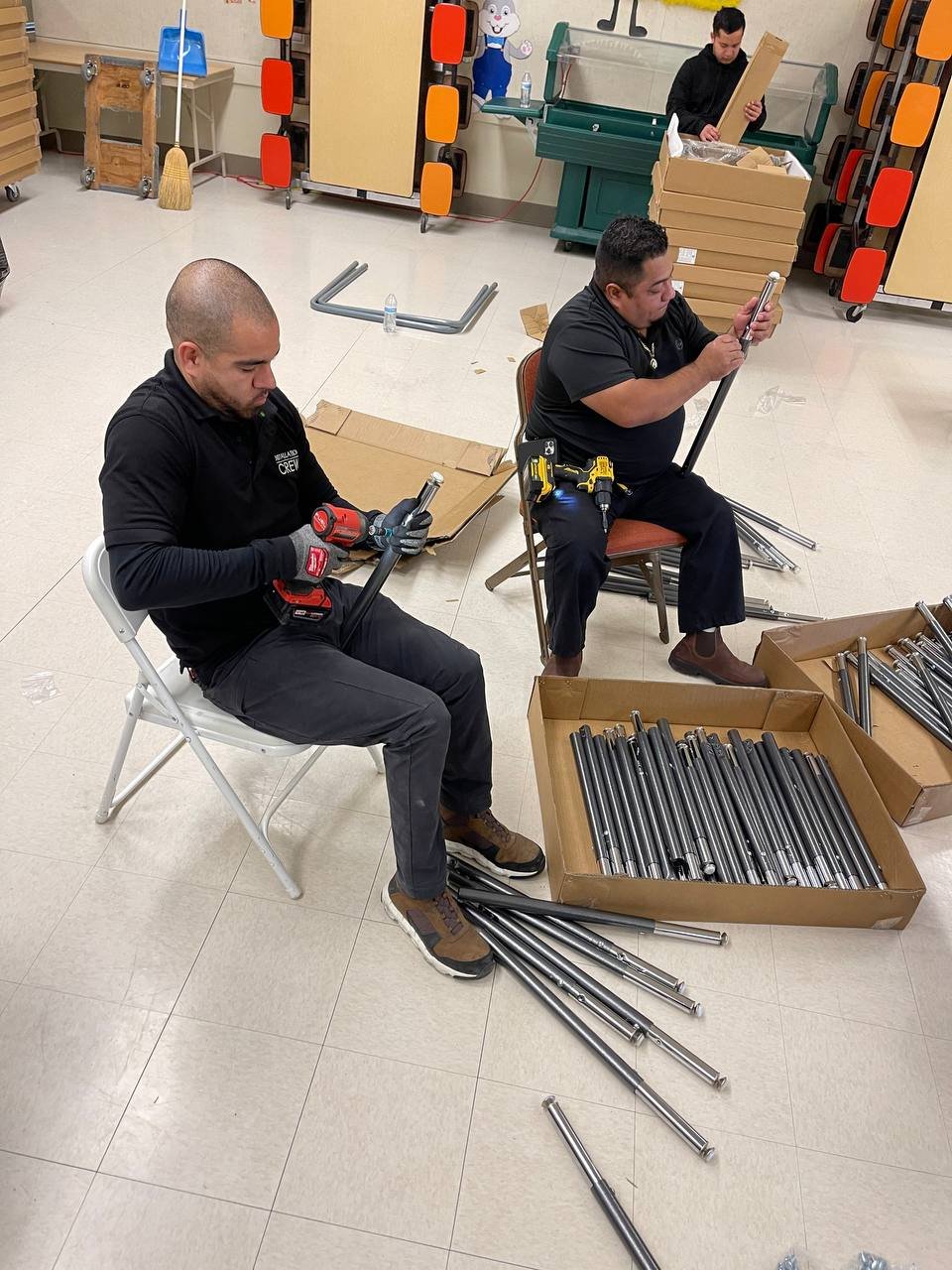 Installers assembling metal legs for school desks and tables