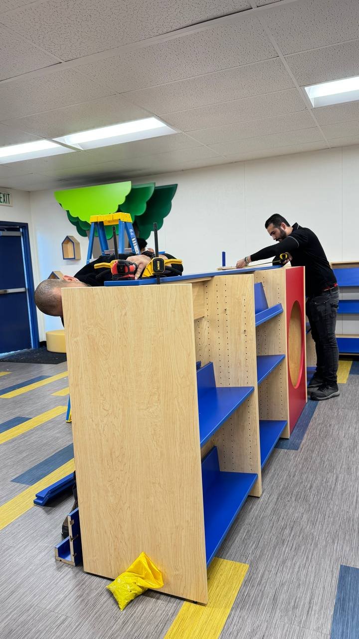 Installers assembling wooden library bookshelves in a school