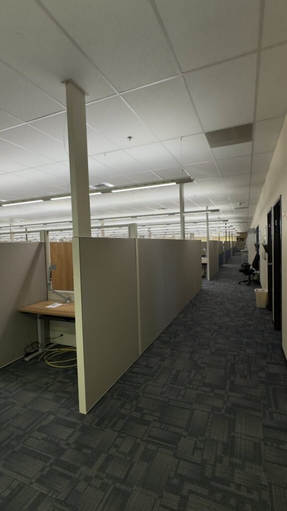 Rows of office cubicle panels and work surfaces beside a central aisle