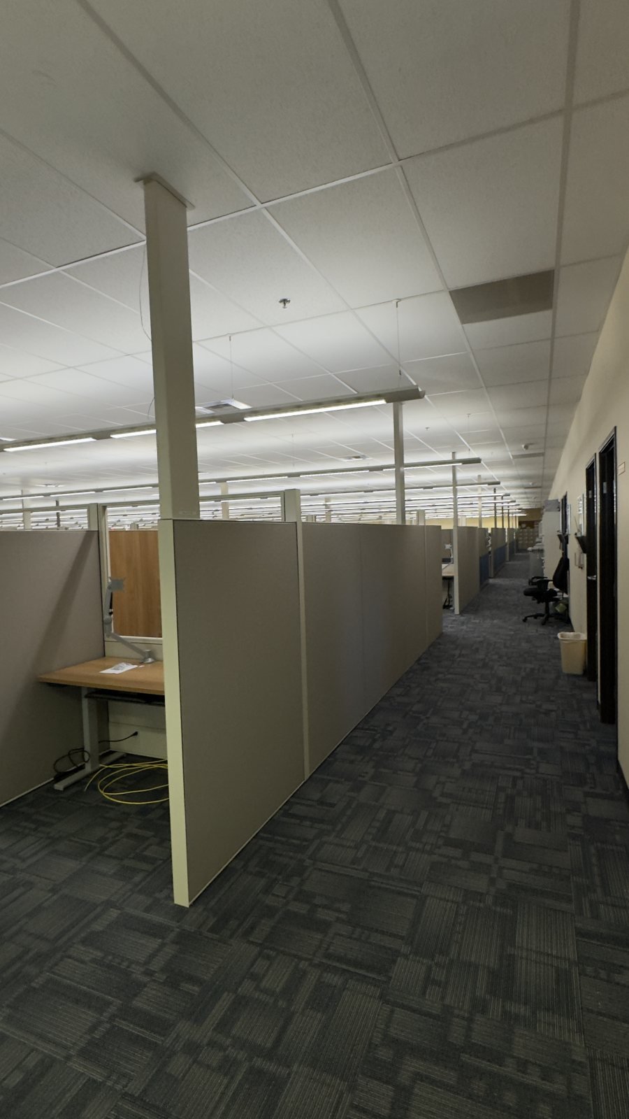 Rows of office cubicle panels and work surfaces beside a central aisle