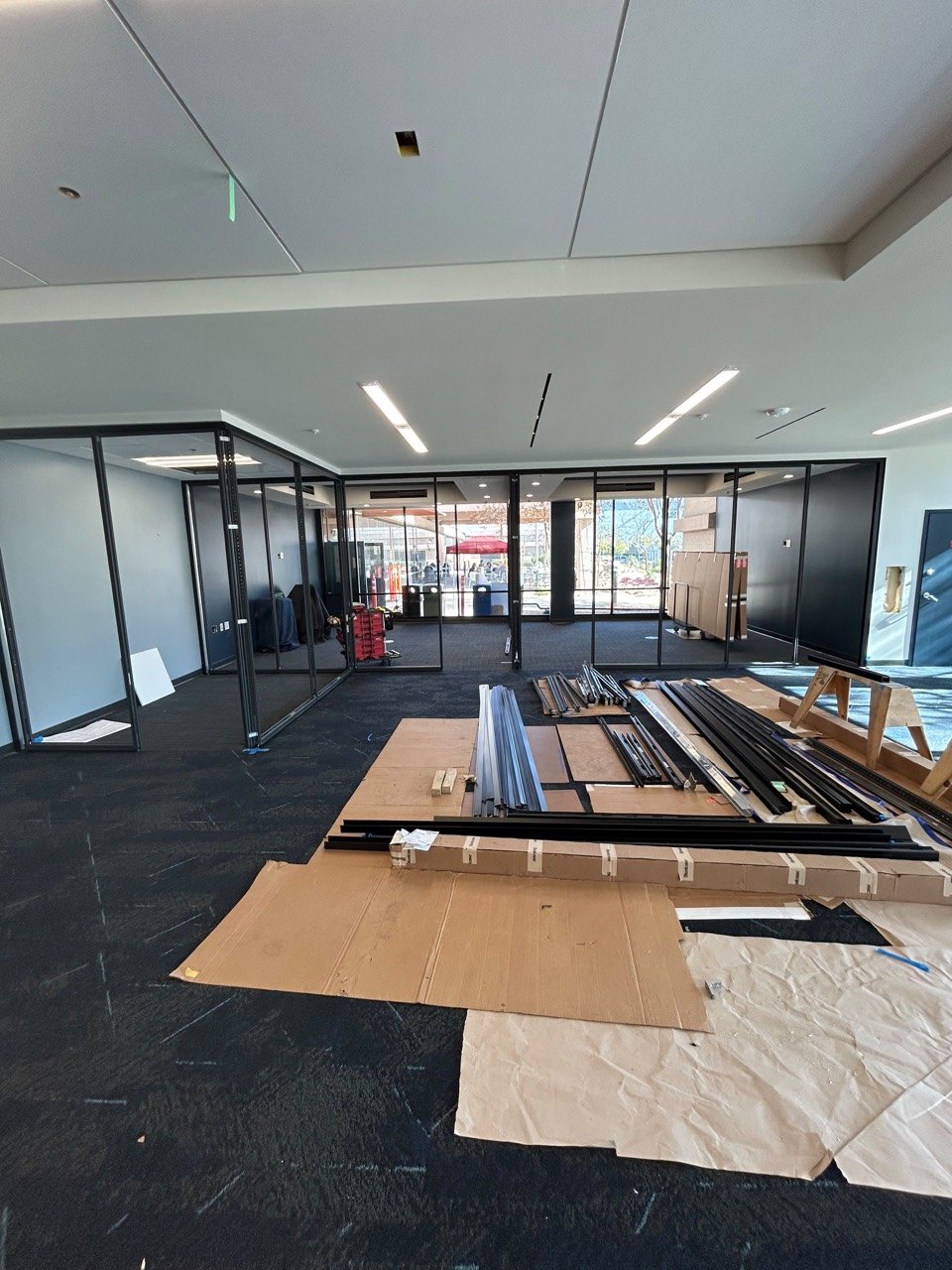 Office partition frames and installation materials staged during a glass wall project